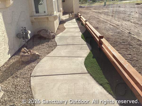 Side walkway with curving concrete, decorative rock, turf, boulders, timber border