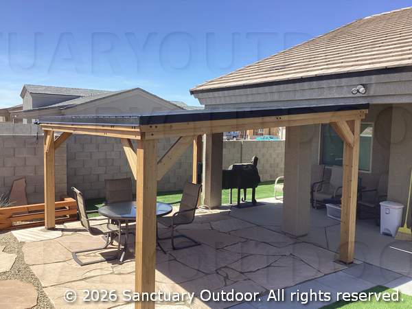 Back yard with pergola over flagstone patio bordered with decorative rock and pewter pavers