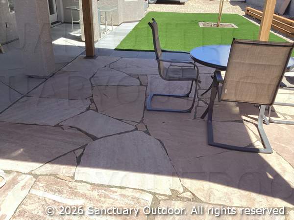 Flagstone patio under back yard pergola overlooking turf and timber border