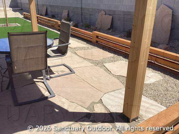 Flagstone patio under back yard pergola with timber border