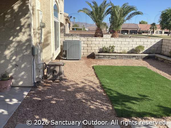 Back yard with decorative rock, turf, masonry planter, bird attracting natural plants